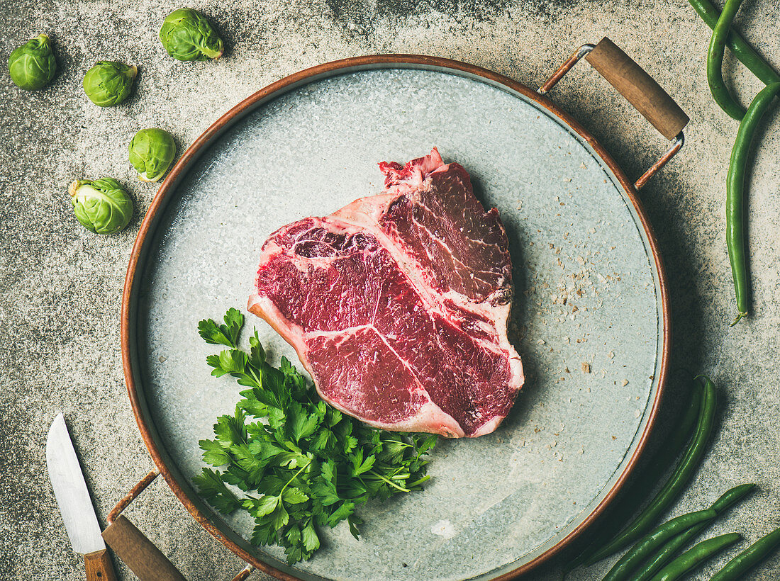 Rohes Dry Aged T-Bone-Steak mit frischer Petersilie und geräuchertem Salz