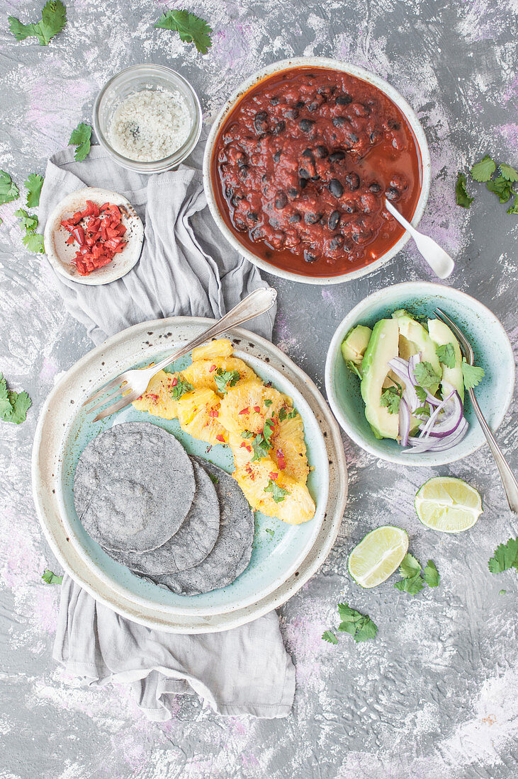 Vegane blaue Maistacos, gebratene Ananas, Avocado mit Salat, schwarze Bohnen mit Tomatensauce
