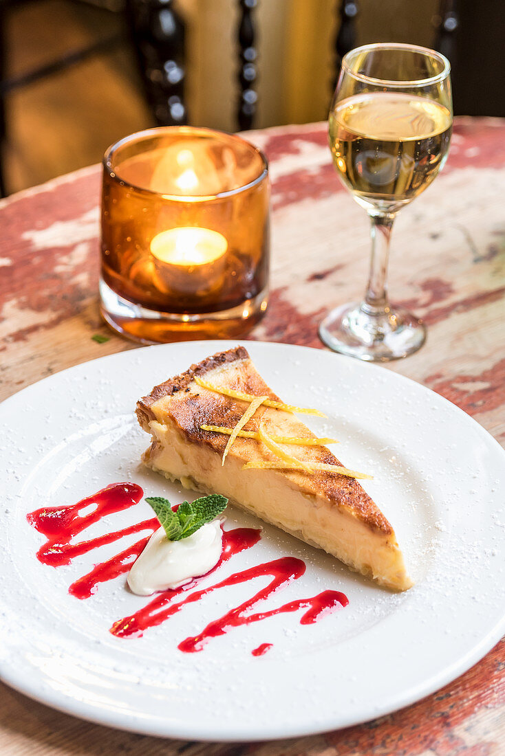 Cheesecake decorated with lemon zest and ice cream on a wooden table