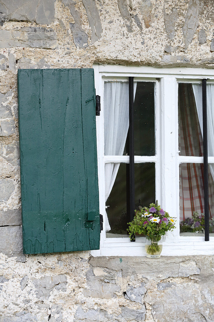 Bunch of wildflowers in window of Alpine cabin