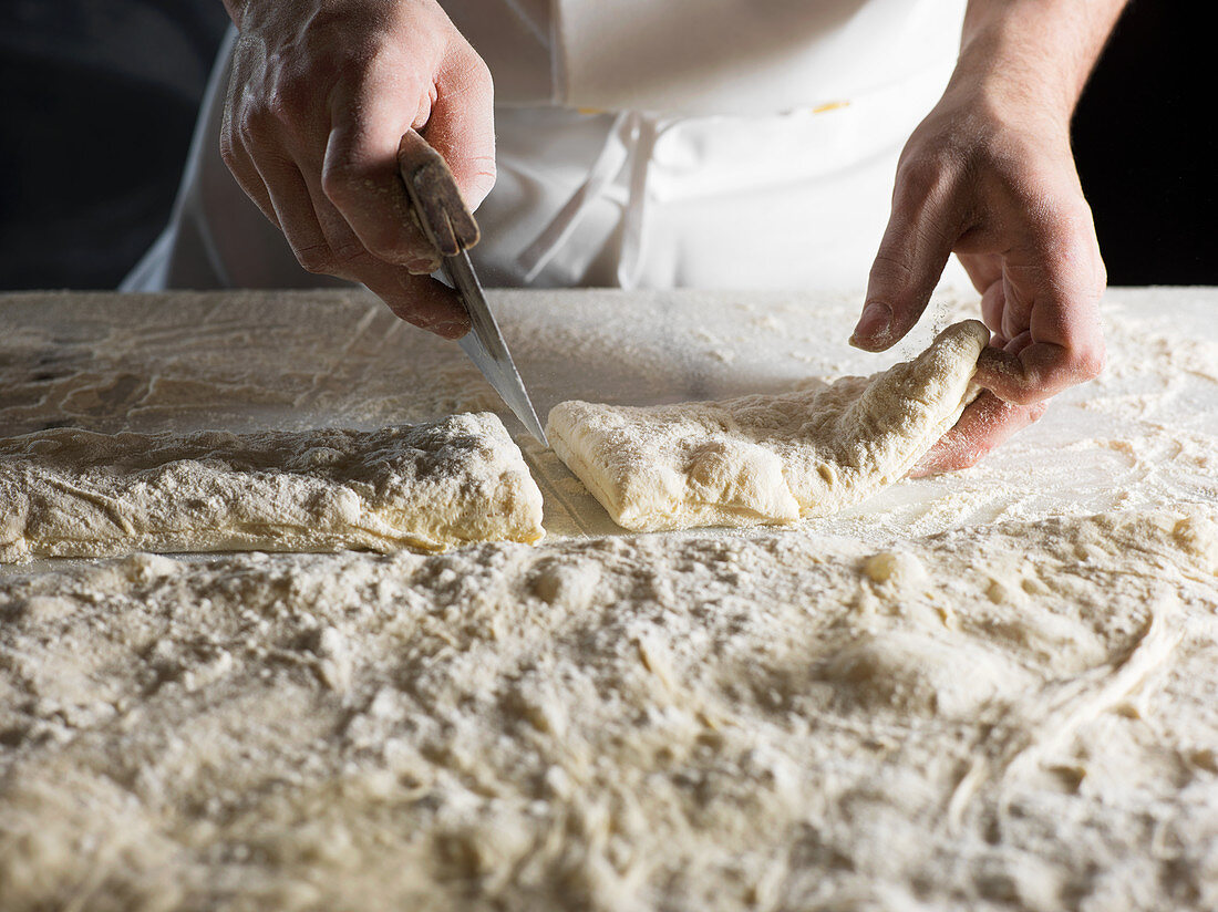 A baker portioning ciabatta bread dough