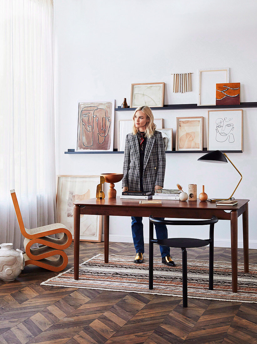 Young woman behind desk, framed artwork on shelves