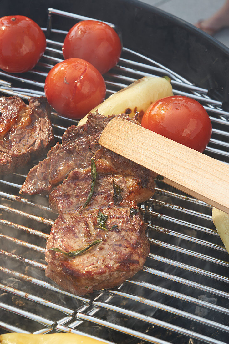 Beef steaks, tomatoes and hot peppers on a grill