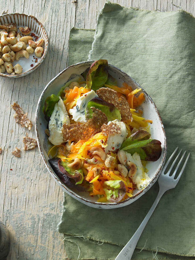 Raw pumpkin salad with cashew nuts, yellow carrots and coriander with blue cheese