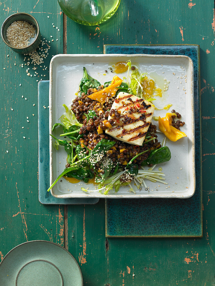Spinach and lentil salad with dried mango, sesame seeds and grilled halloumi