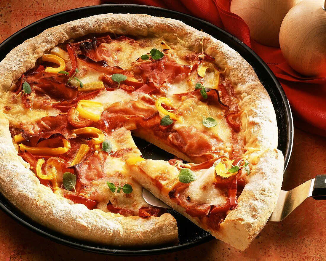 Eine Pizza mit Schinken, Tomaten & Paprika