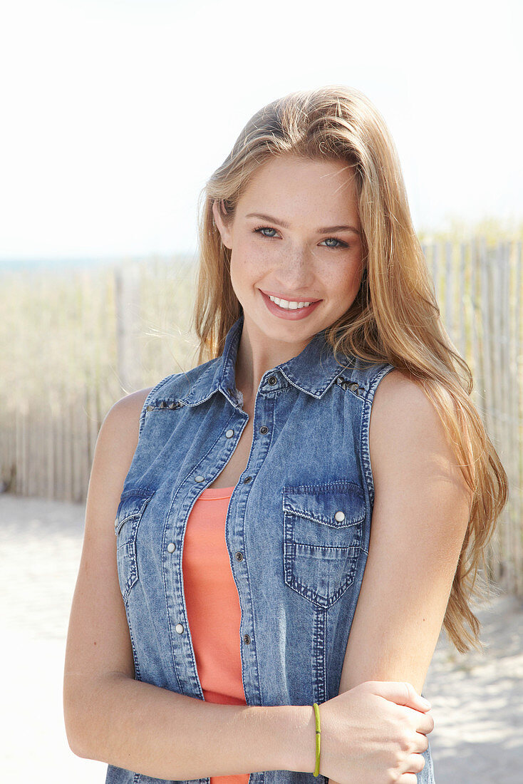 Junge blonde Frau in orangenem Top am Strand