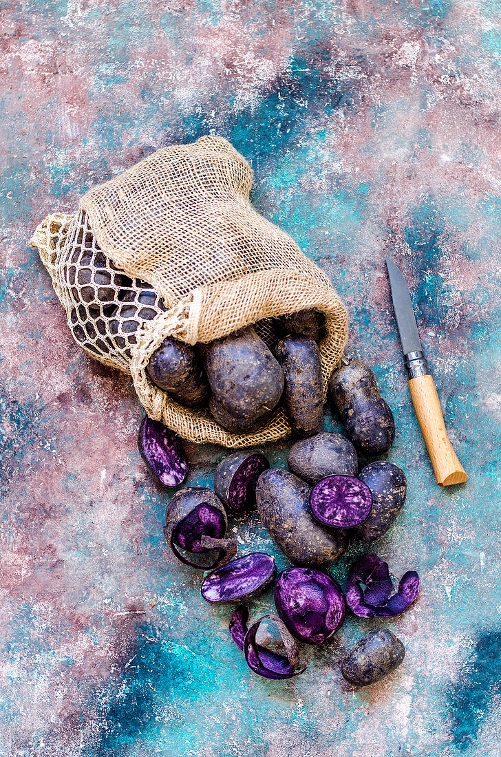 Purple potatoes in a bag and a cleaning knife