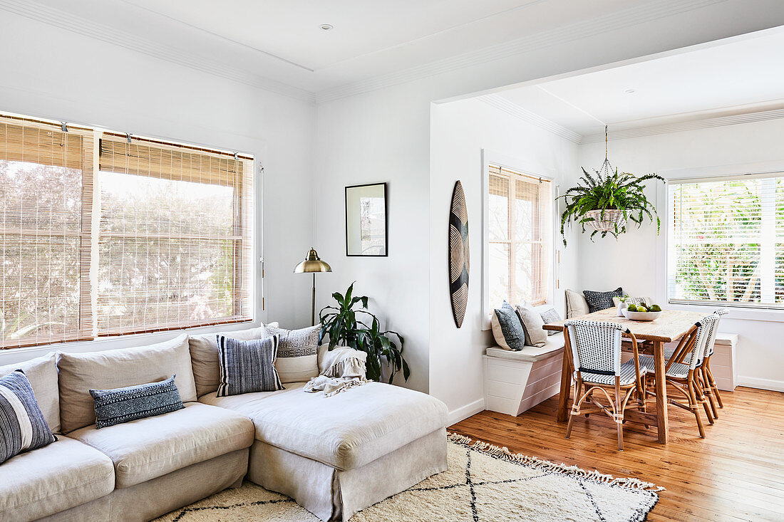 Pale grey sofa in front of open doorway leading into dining room with corner bench