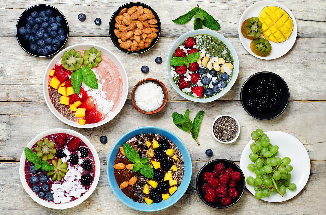 Verschiedene gesunde Smoothie Bowls mit Beeren, Früchten und Nüssen