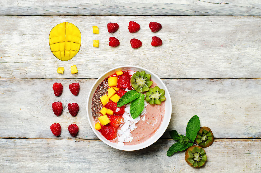 Strawberry smoothies breakfast bowl with coconut flakes, mango, strawberry and Chia seeds