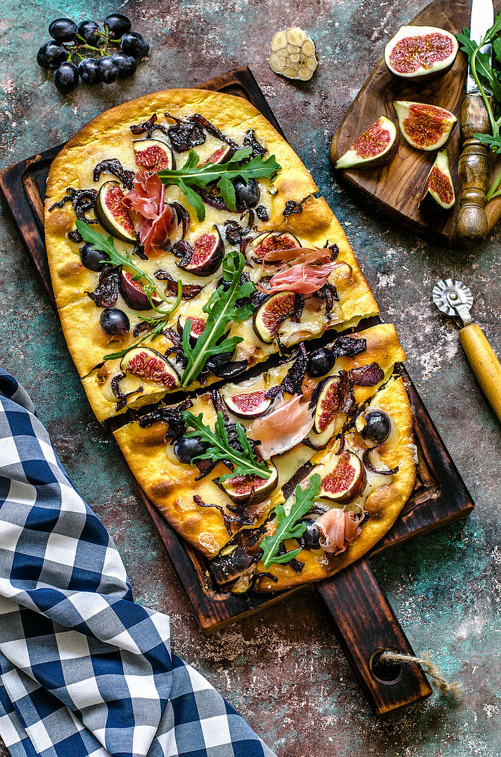 Pizza with mozzarella, figs, black grapes, hamon and arugula