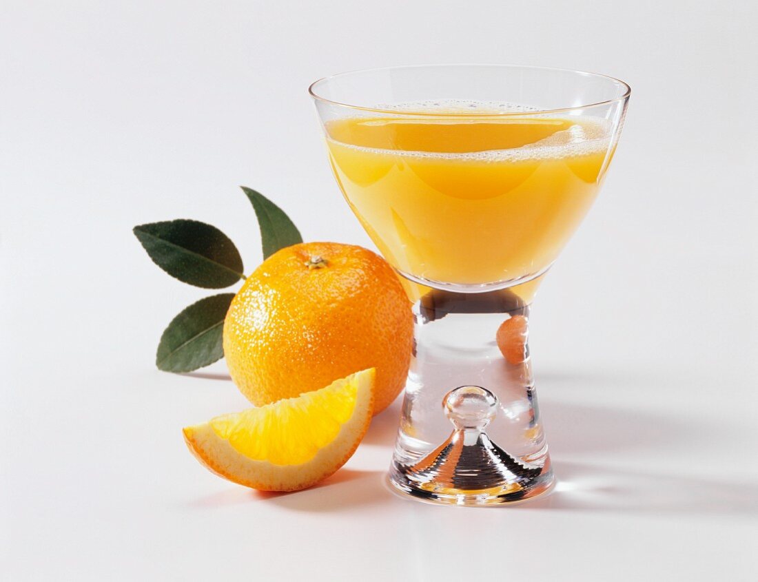 Ein Glas Orangensaft, eine frische Orange & Orangenschnitz