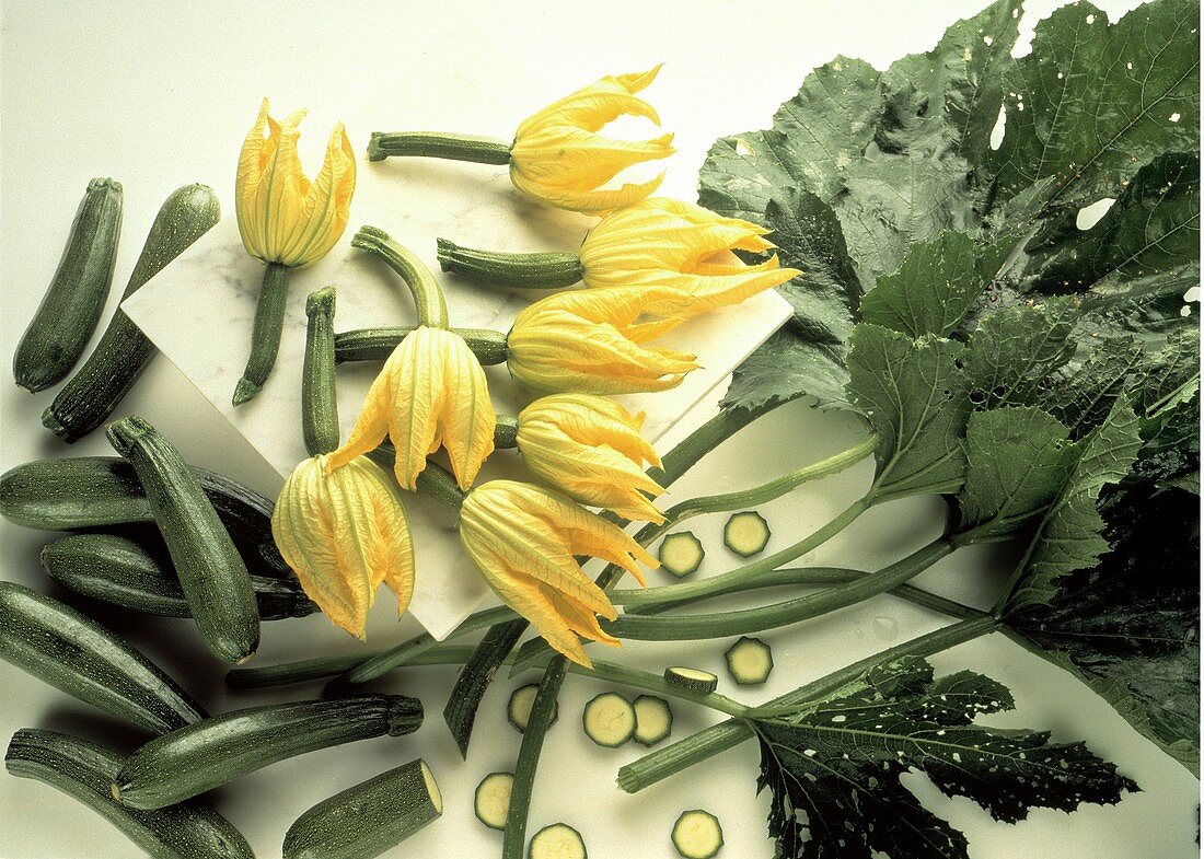 Several Whole Zucchini with Zucchini Blossoms; Slices