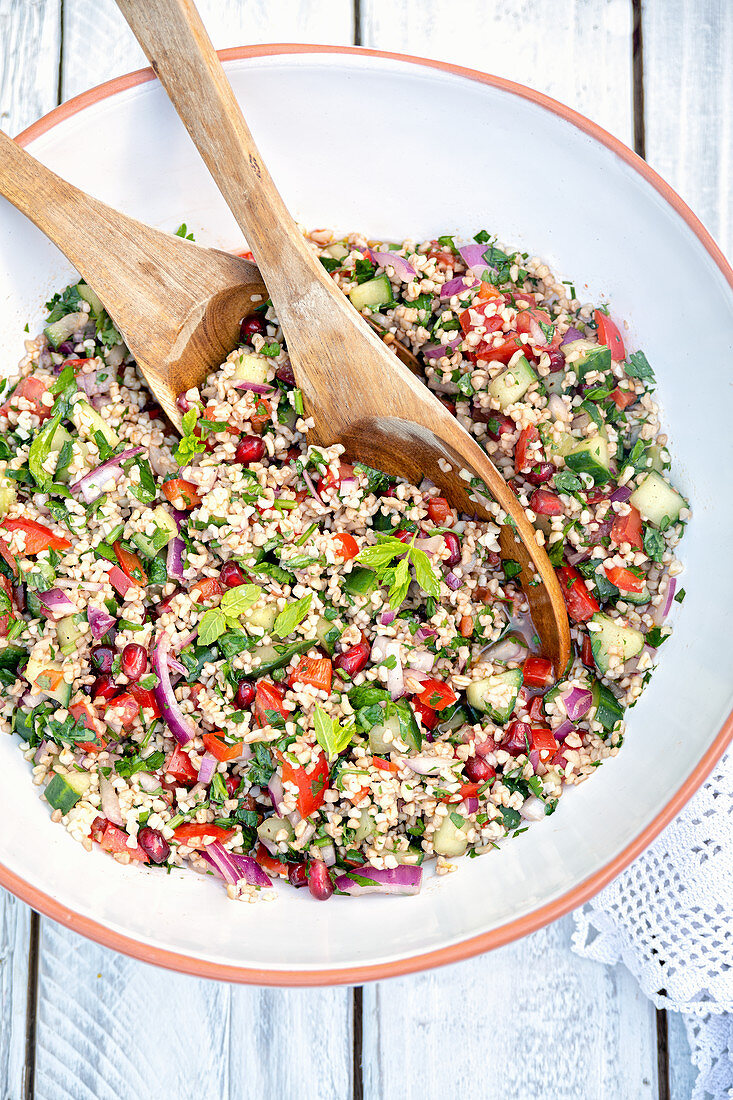 Large bowl of Lebanese tabbouleh salad with bulgur wheat, tomatoes, cucumber, onion, pomegranate