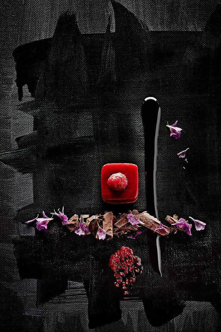 Food art: petit four with raspberries, chocolate and petals