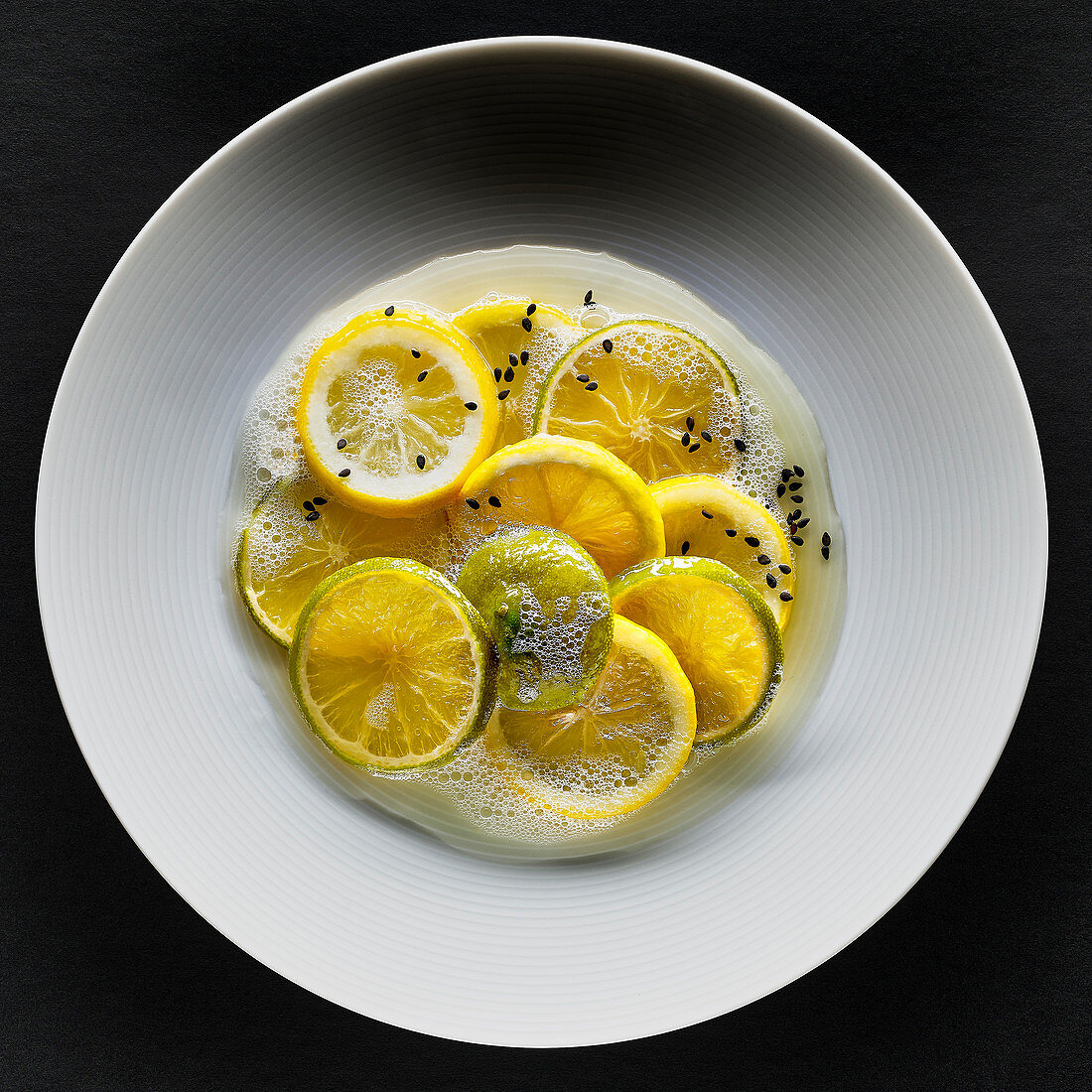 Lemons and limes with black sesame seeds and foam