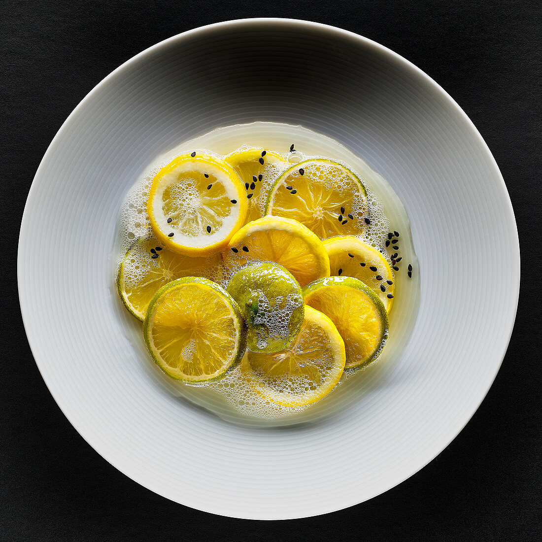 Zitronen und Limetten mit schwarzem Sesam und Schaum