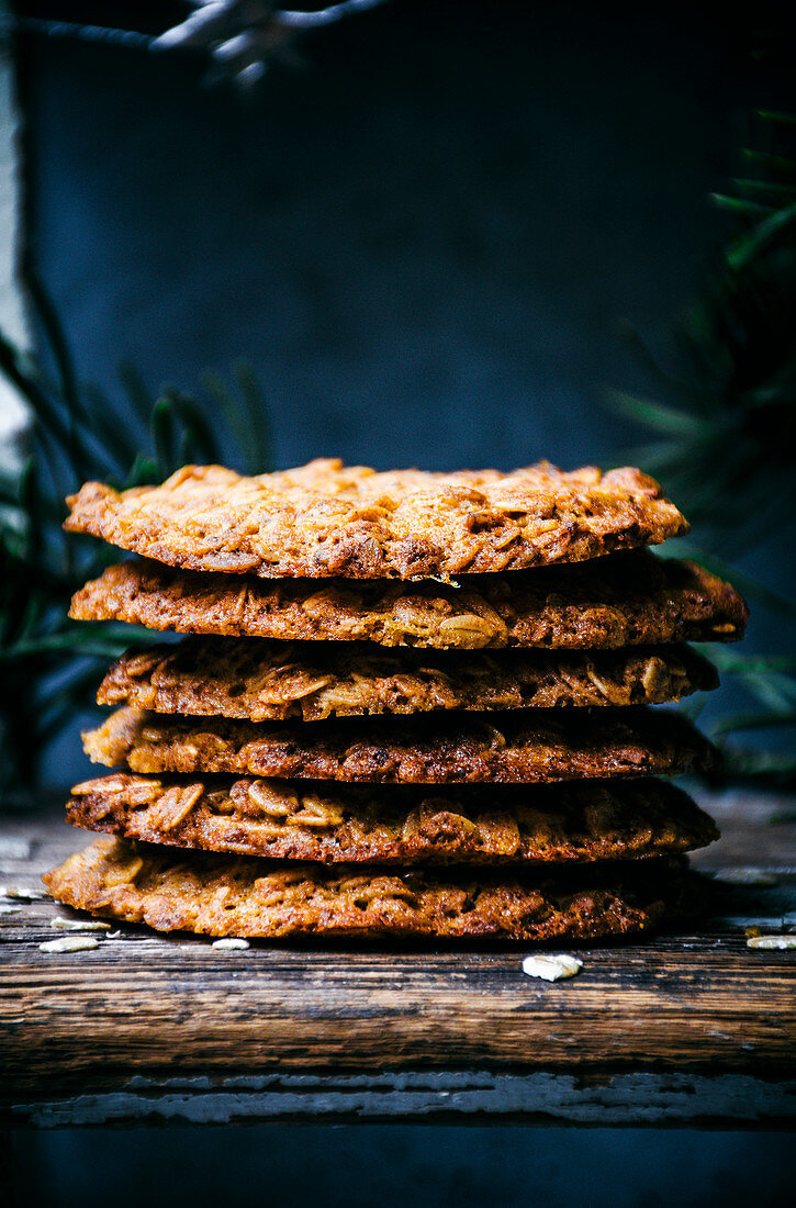 Thin honey and oat cookies stacked with greenery