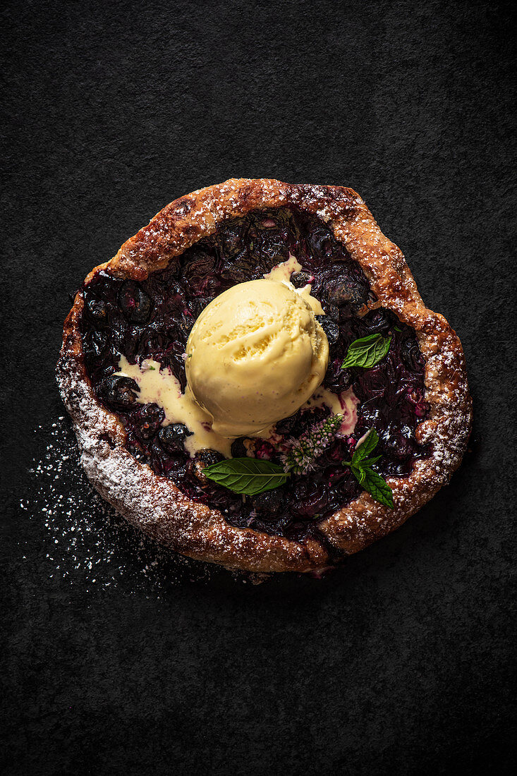 Blueberry galette with ice cream on a black slate