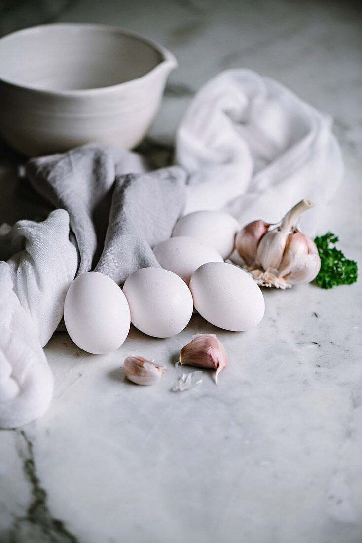 White eggs with garlic cloves on a marble worktop in a kitchen