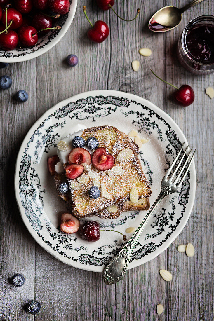 French Toast mit Mandeln, Kirschen und Blaubeeren zum Frühstück (Aufsicht)
