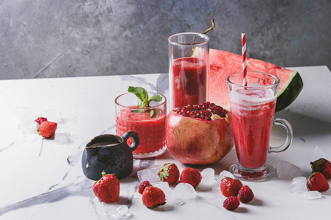 Drei verschiedene rote Fruchtsmoothies mit Erdbeere, Wassermelone und Granatapfel