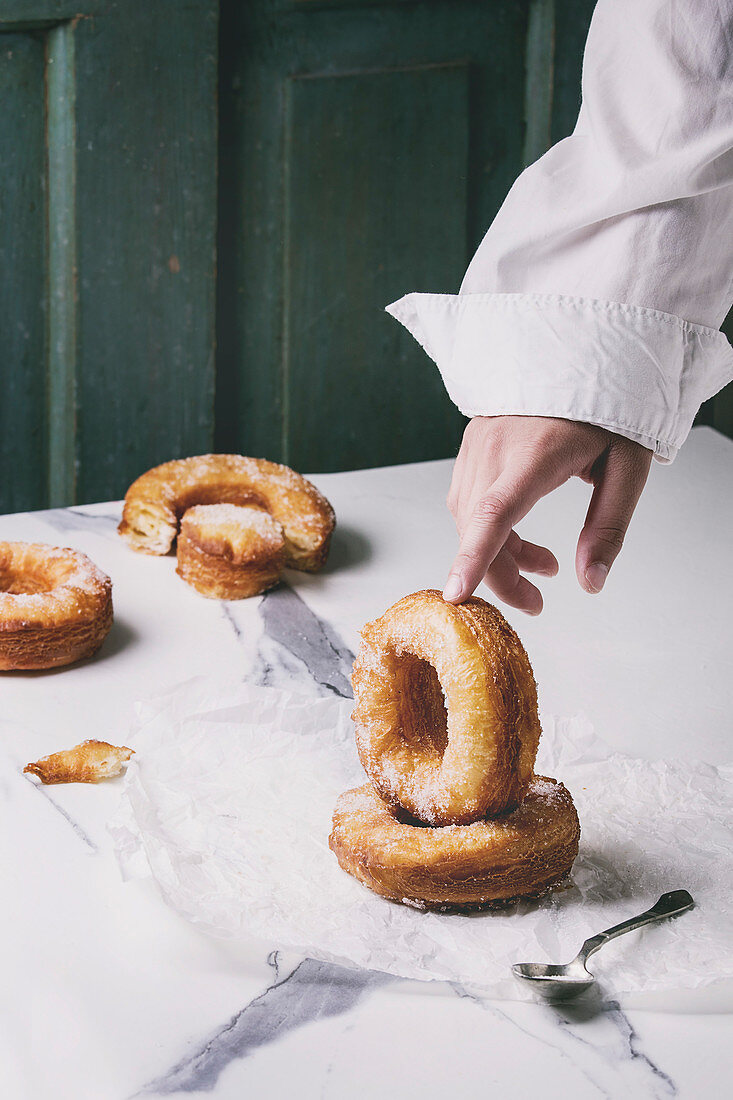 Boy's hand hold homemade puff pastry deep fried donuts or cronuts with sugar