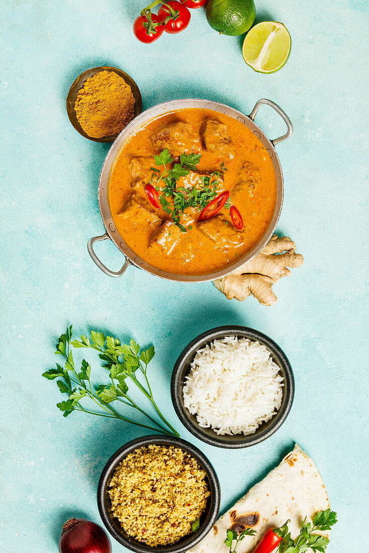 Traditionelles indisches Curry mit Zutaten, Reis und Naan-Brot (Aufsicht)