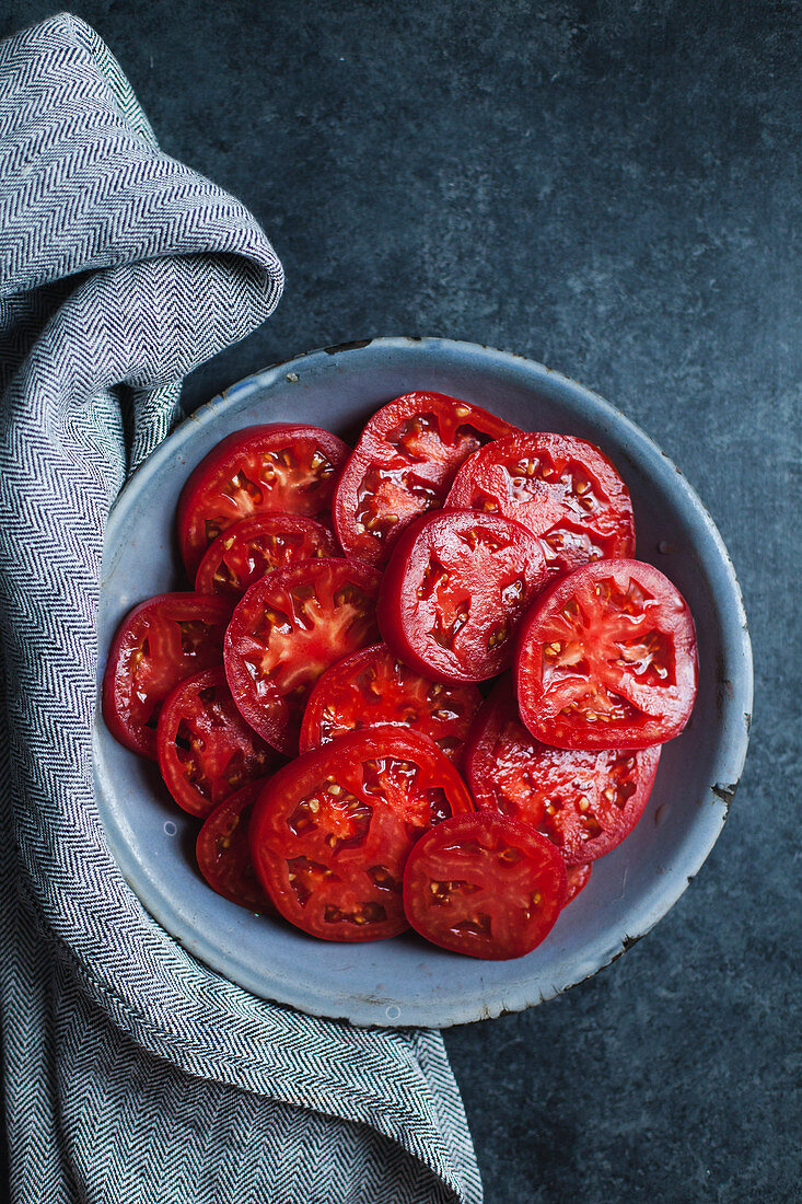 Tomatenscheiben auf blauem Teller (Aufsicht)