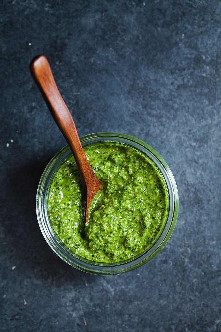 Pesto in glass jar with wood spoon
