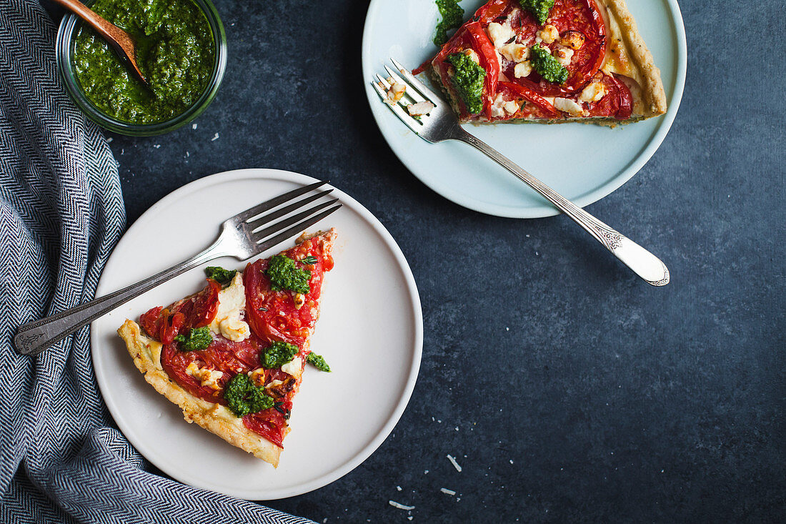 Zwei Stücke Tomatentarte mit Pesto auf Tellern (Aufsicht)