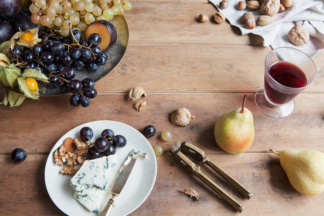 Blauschimmelkäse mit Trauben und Nüssen serviert mit Rotwein auf rustikalem Holztisch