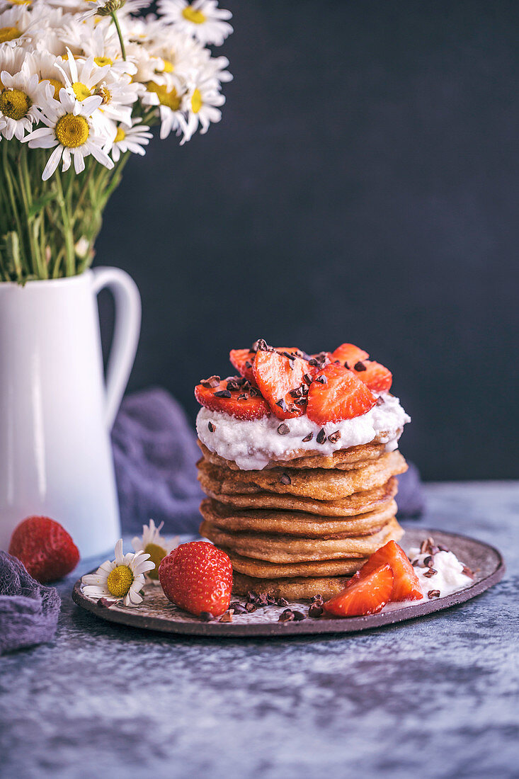 Stack of pancakes with strawberries and cream