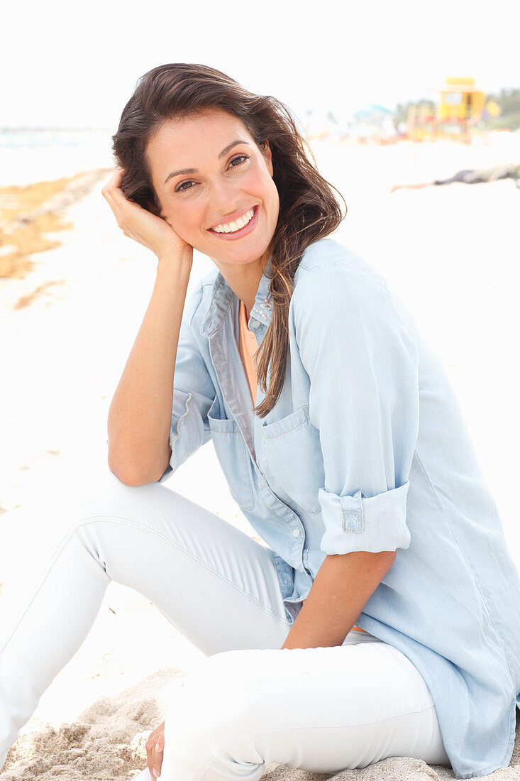 A brunette woman wearing a denim shirt and white trousers