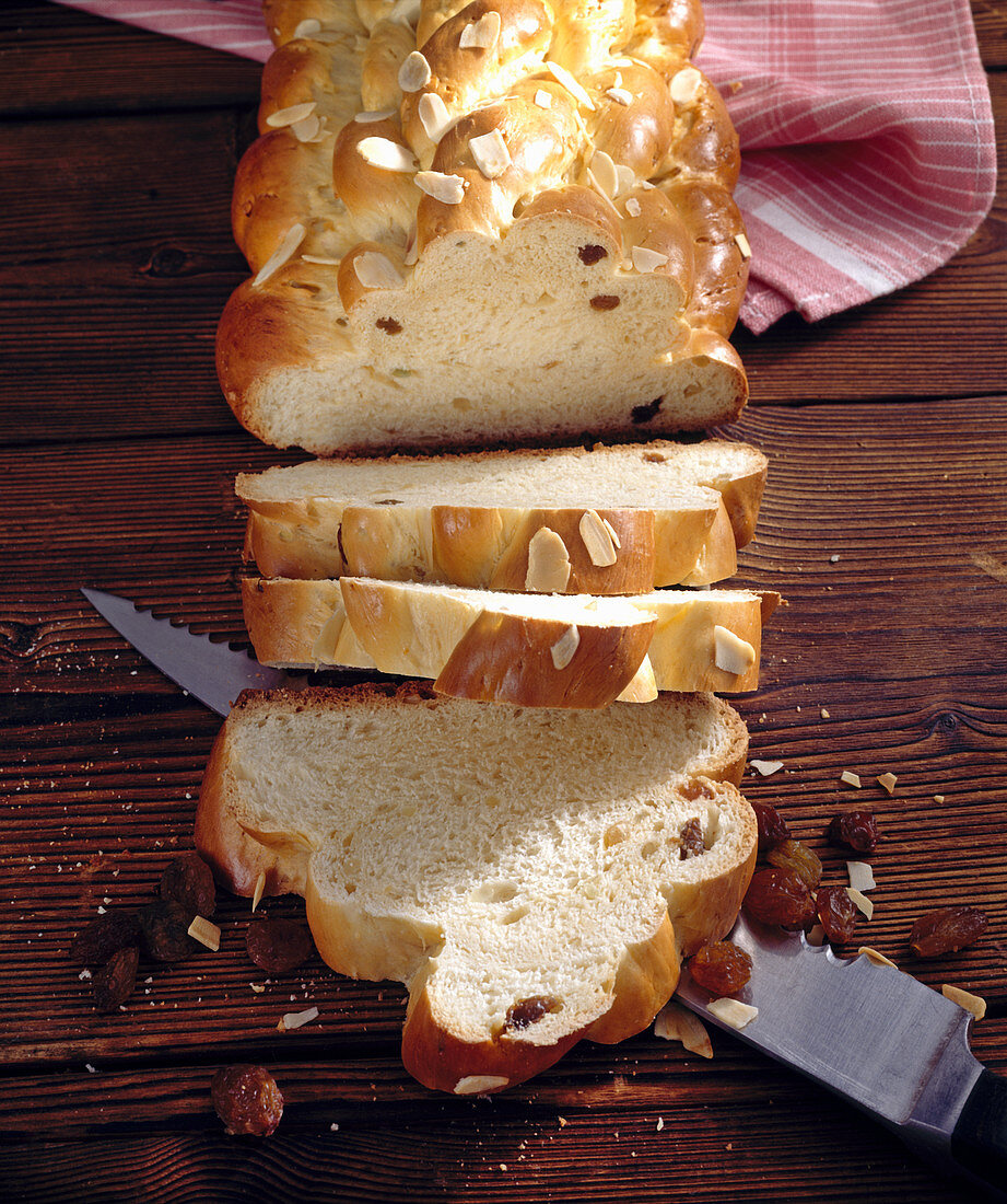 Sliced Bohemian bread with a knife on a wooden background
