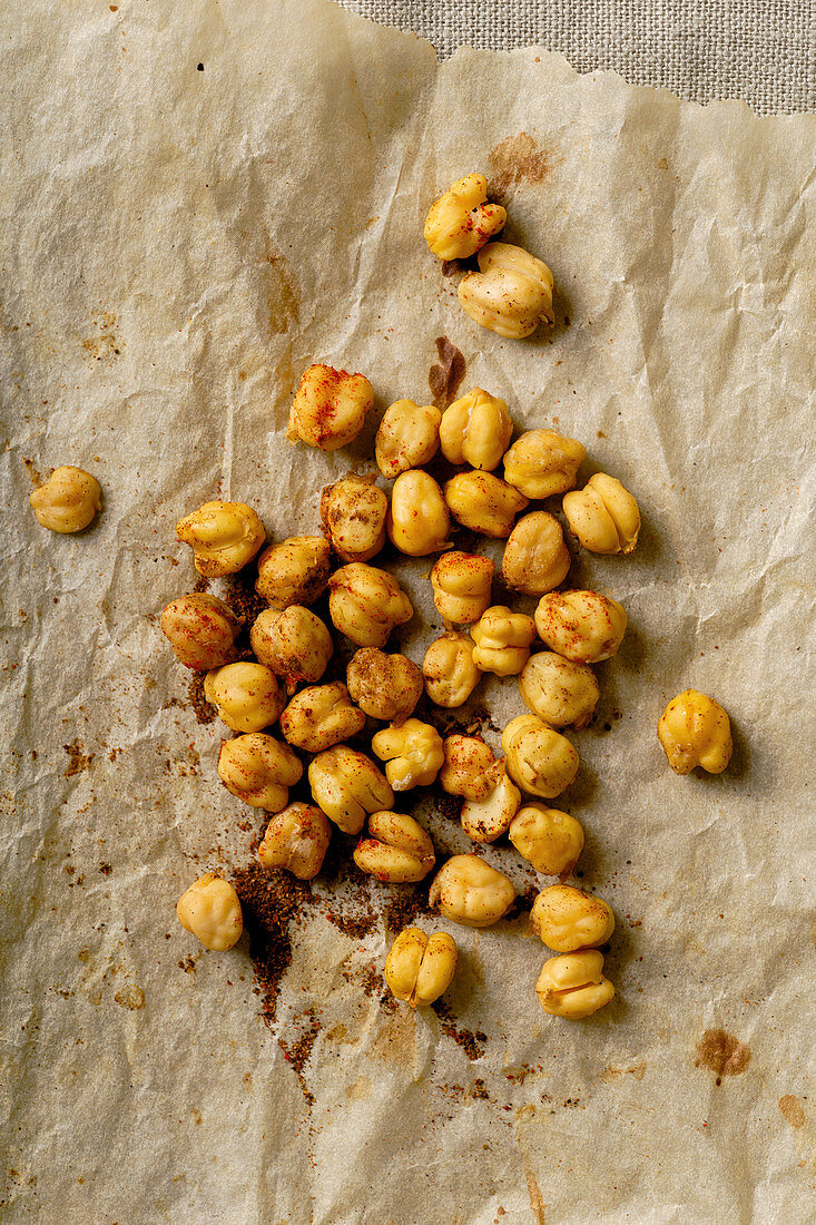 Roasted chickpeas with paprika, salt and spices on baking paper sheet and linen