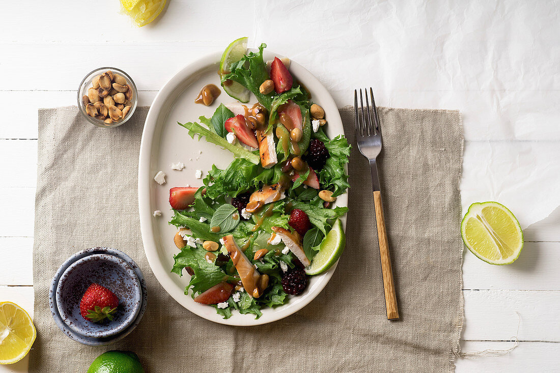 Overhead image of fresh summer salad with berries, roasted chicken and sweet peanut dressing