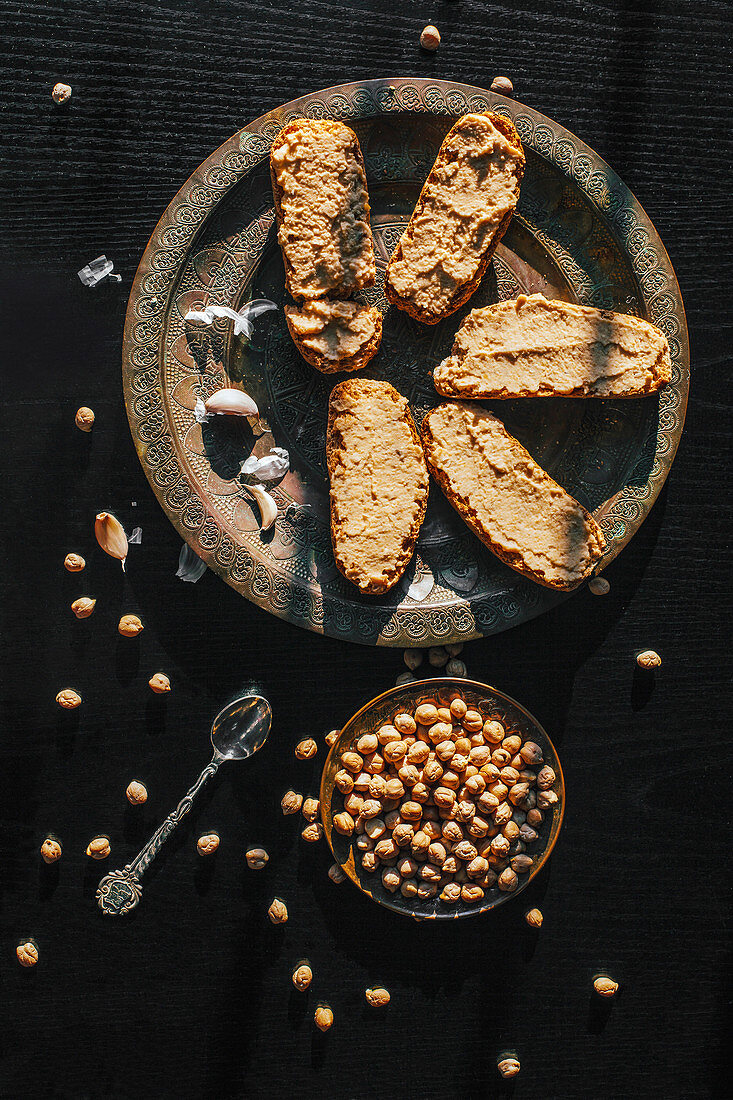 Brotscheiben mit selbstgemachtem Hummus auf schwarzem Untergrund