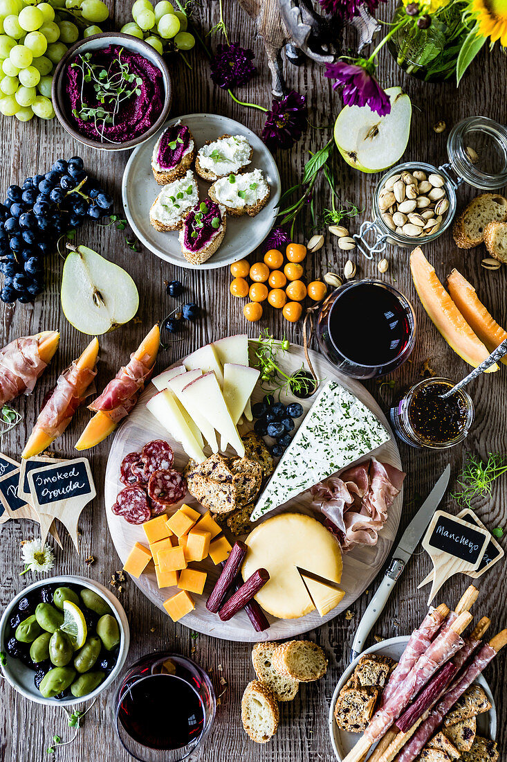 Vorspeisentableau mit Wurst, Käse, Obst, Dips und Rotwein (Aufsicht)