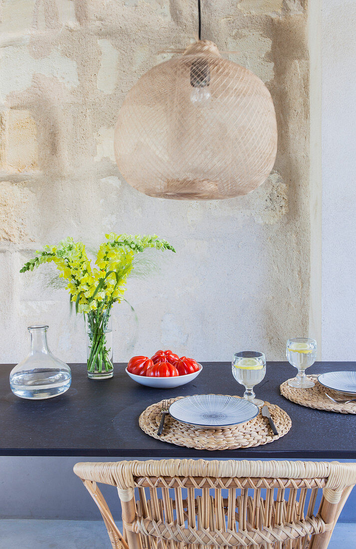 Set dining table below wicker lampshade on terrace