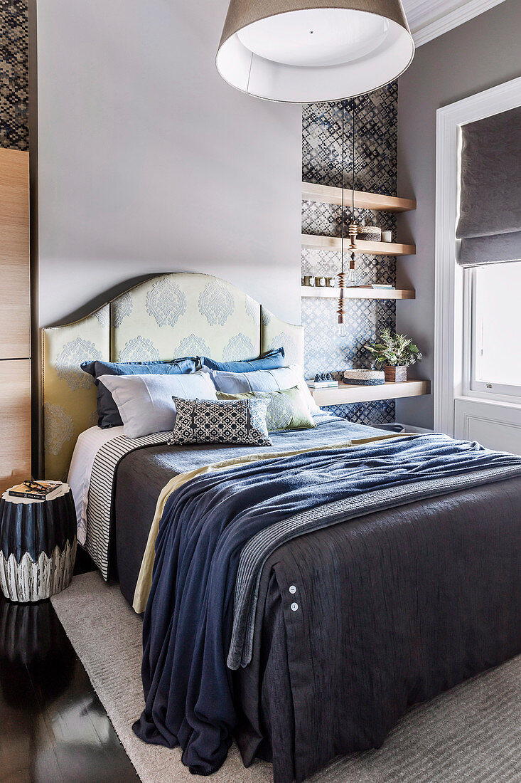 Bett mit Accessoires in Blautönen und eingespannte Regalbretter im Schlafzimmer
