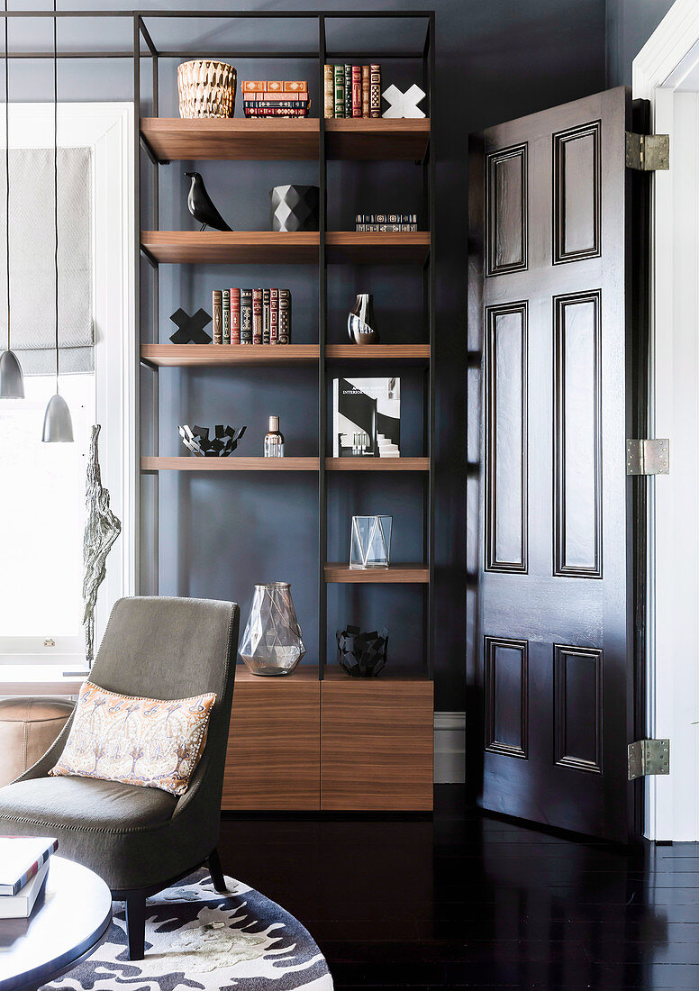 Bookshelf against dark wall next to open door in living room