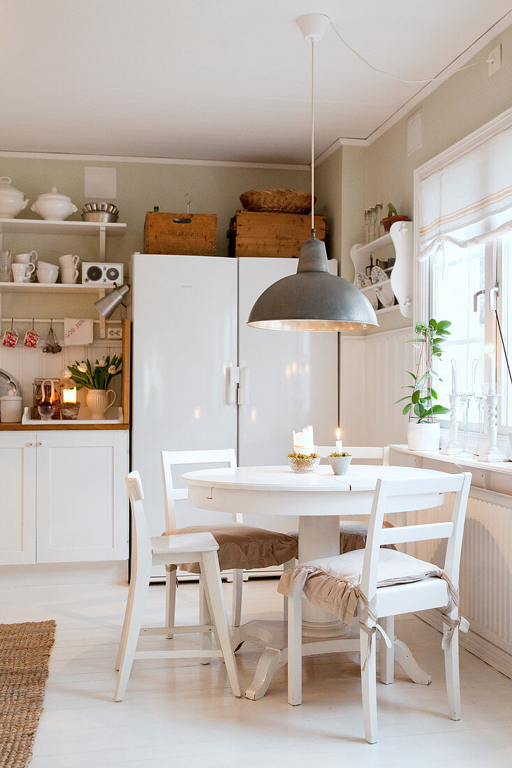 Runder Esstisch mit Stühlen in ländlicher Küche im Weiß