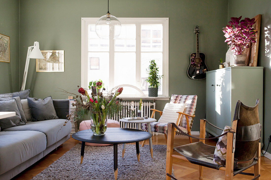 Polstersofa, Coffeetable und Armlehnstühle im Wohnzimmer mit grünen Wänden