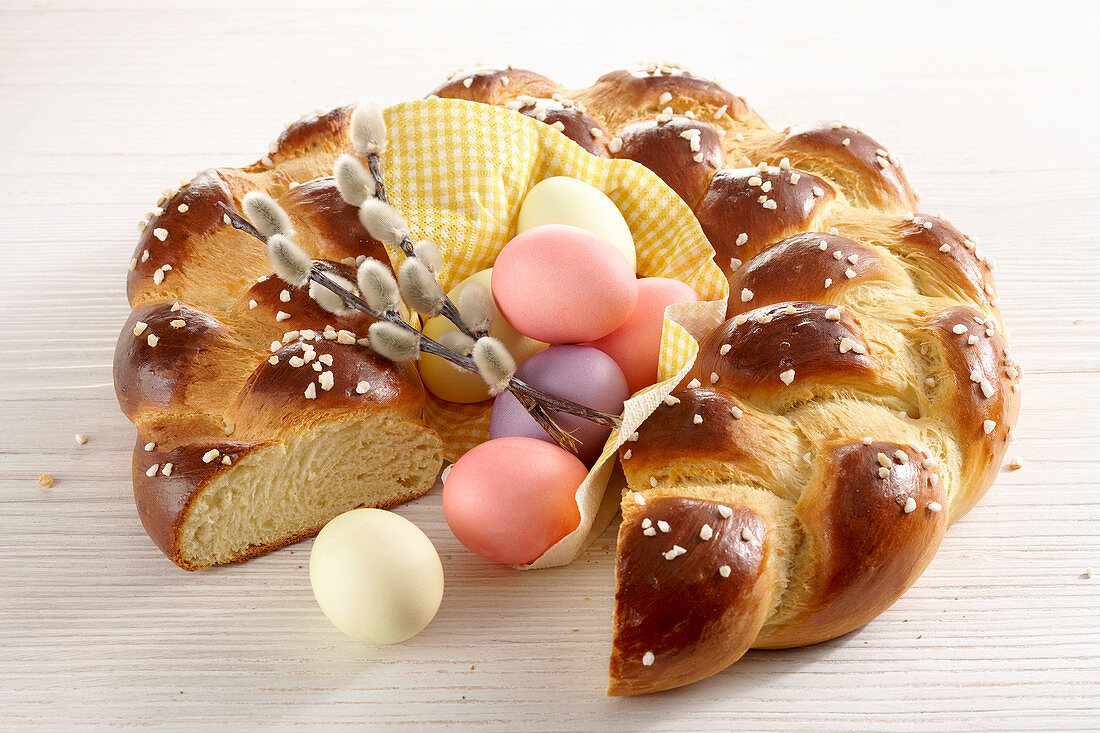 A yeast wreath for Easter breakfast with colorful easter eggs and catkins