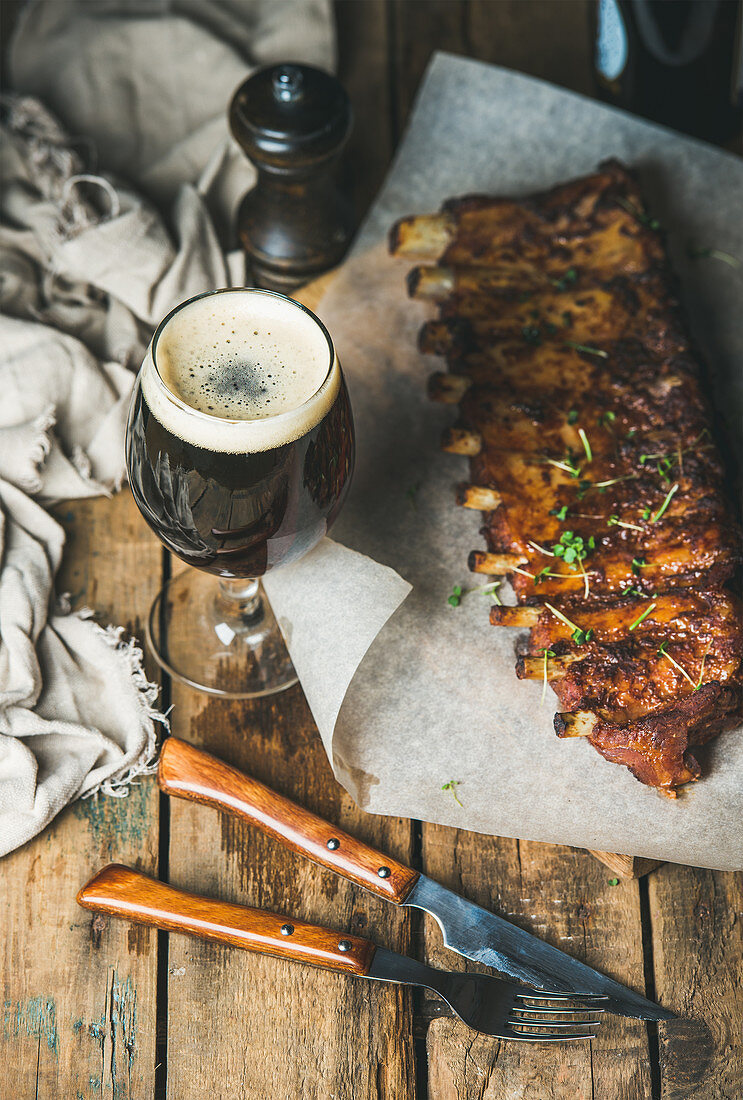 Roasted pork ribs with garlic, rosemary and glass of dark beer