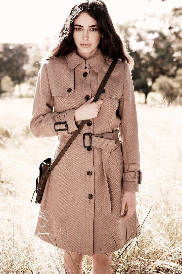 A dark-haired woman wearing a woollen coat with a shoulder bag