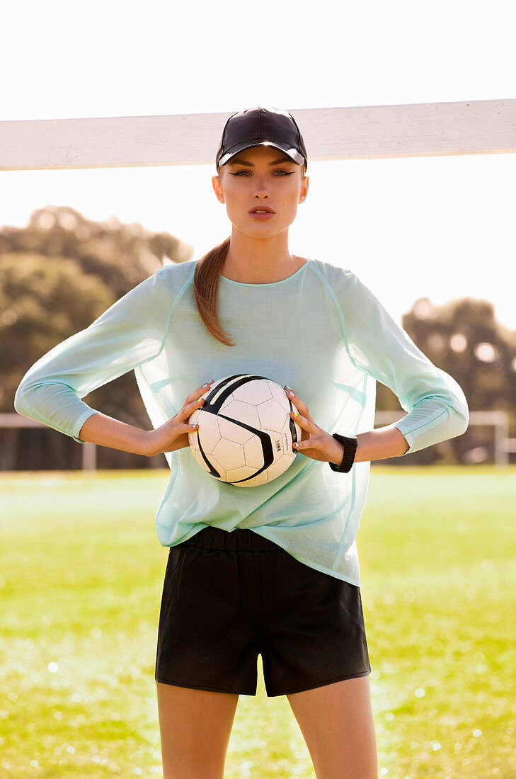 A young woman wearing sports clothes holding a football