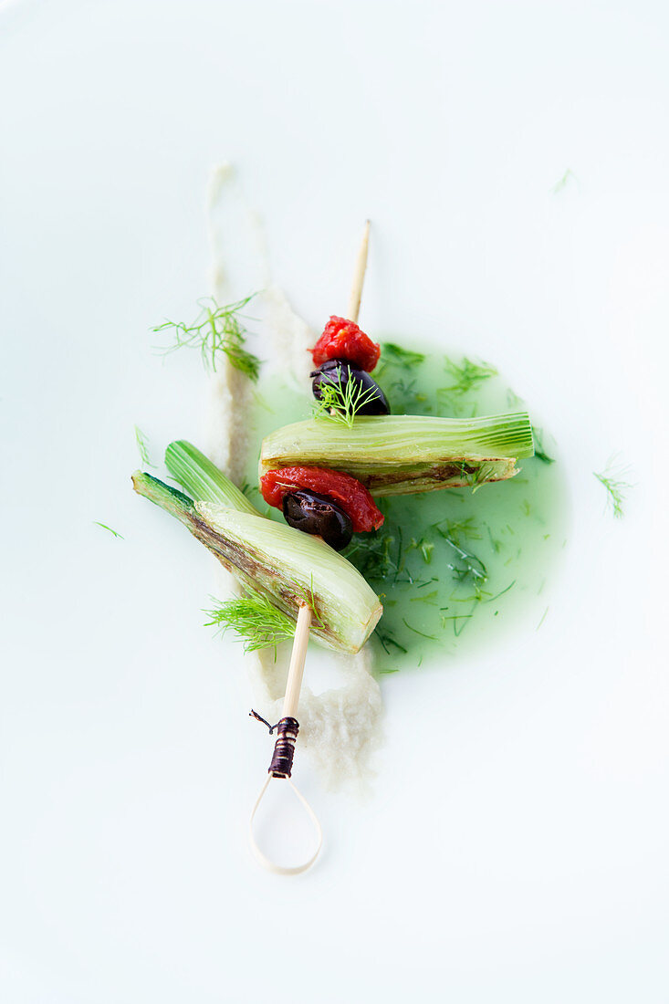 Fennel broth with a skewer of fennel, tomato and olive